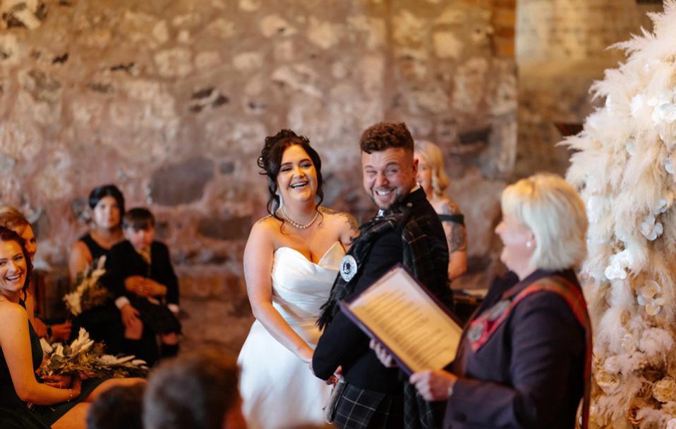 A couple laughing with Victoria during their ceremony