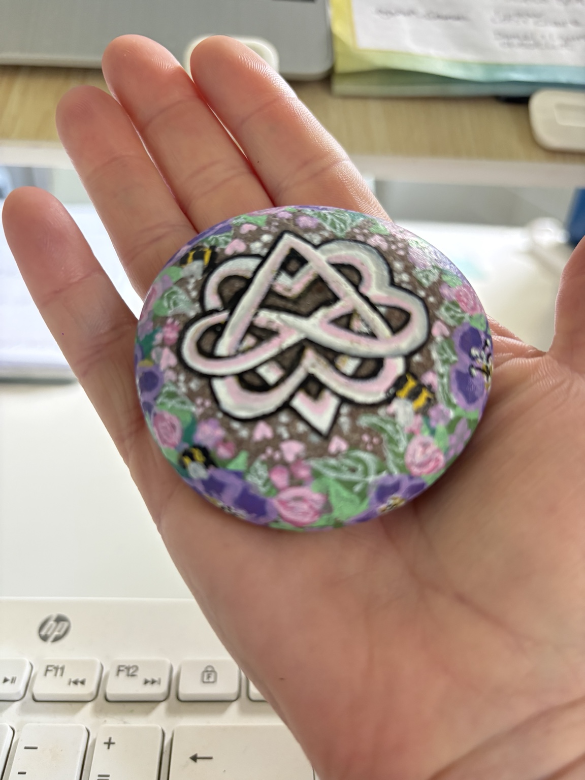 A hand-painted oathing stone decorated with Celtic knotwork, flowers and bees