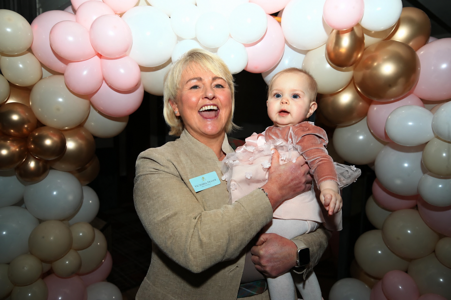 Victoria holding a baby at a naming celebration